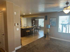Kitchen featuring a kitchen bar, ceiling fan, light carpet, a center island, and a textured ceiling