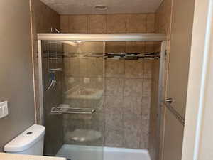 Bathroom featuring tiled shower and a textured ceiling