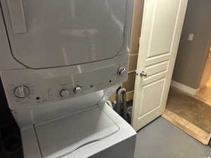 Laundry area featuring stacked washer and clothes dryer and baseboards
