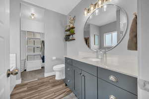 Full bathroom with a walk in closet, vanity, and light wood-style floors