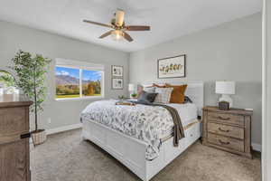 Bedroom featuring a mountain view, ceiling fan, and light colored carpet