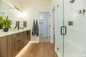 Bathroom featuring a stall shower, double vanity, light wood-type flooring, and a spacious closet
