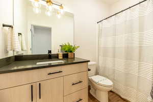 Full bath with a shower with shower curtain, vanity, and wood finished floors