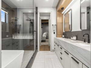 Ensuite bathroom with double vanity, a stall shower, and light tile patterned flooring