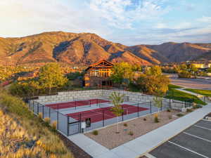 View of tennis court featuring a mountain view, a gate, and a patio area