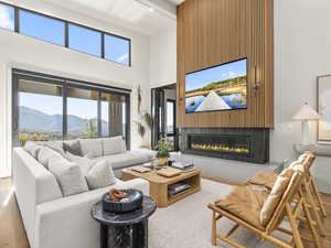 Living room featuring a high ceiling, a glass covered fireplace, and wood finished floors