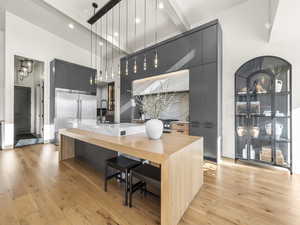 Kitchen with modern cabinets, decorative light fixtures, light wood finished floors, a large island, and gray cabinetry