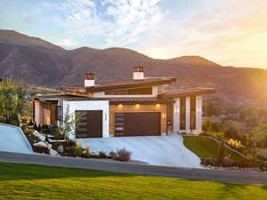 View of front facade with a chimney, a mountain view, a front yard, and driveway