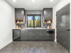 Bar area with open shelves, backsplash, wine cooler, and gray cabinetry