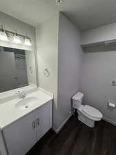 Full bathroom with a textured ceiling, vanity, dark wood-style flooring, and a shower