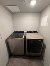 Washroom with a textured ceiling, washer and clothes dryer, and dark carpet