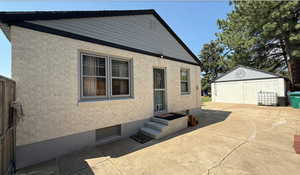 Back of property featuring an outdoor structure, entry steps, and stucco siding