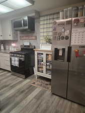 Kitchen featuring stainless steel appliances, white cabinetry, and light countertops