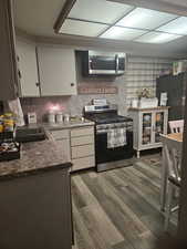 Kitchen with stainless steel appliances, dark wood-style flooring, and white cabinetry