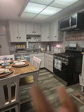 Kitchen featuring stainless steel appliances, white cabinetry, tasteful backsplash, and dark wood-type flooring