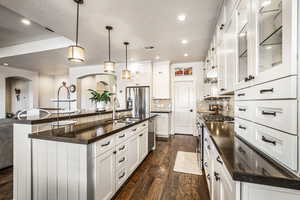 Kitchen with pendant lighting, tasteful backsplash, glass insert cabinets, stainless steel appliances, and white cabinetry