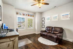 Office space featuring dark wood-style flooring, ceiling fan, and a textured ceiling