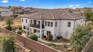 Back of property with a fenced backyard, stucco siding, a balcony, a tile roof, and a residential view