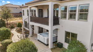 Back of house featuring a hot tub, a patio area, stucco siding, a balcony, and a tile roof
