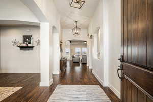 Entrance foyer with dark wood-type flooring, arched walkways, and a high ceiling