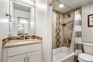 Full bathroom featuring shower / bath combo, vanity, and decorative backsplash