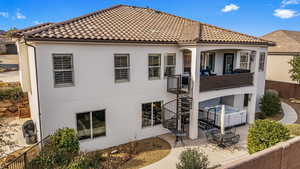 Back of property with a tile roof, a fenced backyard, stucco siding, a hot tub, and a patio area