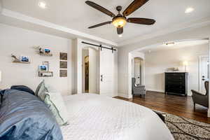 Bedroom with a barn door, recessed lighting, dark wood-style flooring, a ceiling fan, and arched walkways