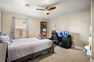 Carpeted bedroom featuring ceiling fan and an office area