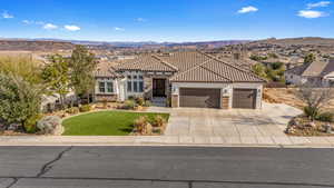 Mediterranean / spanish-style house with a garage, a front lawn, a mountain view, driveway, and stone siding