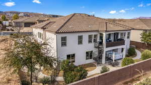 Back of property featuring a fenced backyard, a balcony, stucco siding, a tiled roof, and a patio