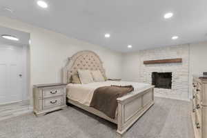 Bedroom featuring a fireplace, light colored carpet, and recessed lighting