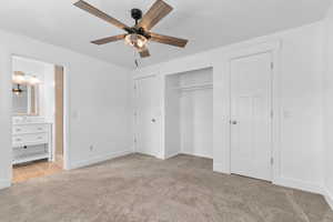 Unfurnished bedroom with light carpet, a closet, connected bathroom, and a ceiling fan