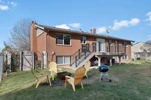 Back of house featuring a gate, a fire pit, a chimney, brick siding, and a wooden deck