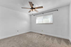Carpeted empty room featuring baseboards and a ceiling fan