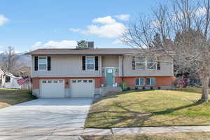 Raised ranch with brick siding, a garage, and concrete driveway
