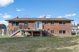 Rear view of house featuring brick siding and a wooden deck