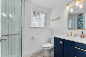 Full bath featuring vanity, light wood-type flooring, and a tile shower