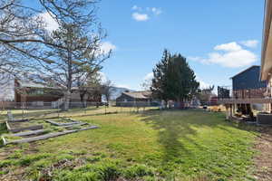Fenced backyard featuring a wooden deck and a garden