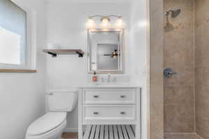 Bathroom featuring vanity, a tile shower, and ceiling fan