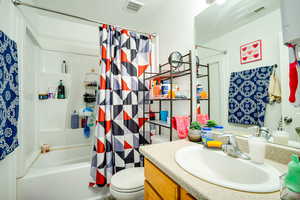 Bathroom featuring vanity, shower / bath combination with curtain, a textured ceiling, and water heater