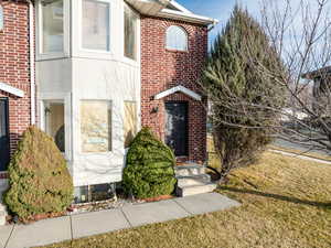 Property entrance with brick siding and a lawn