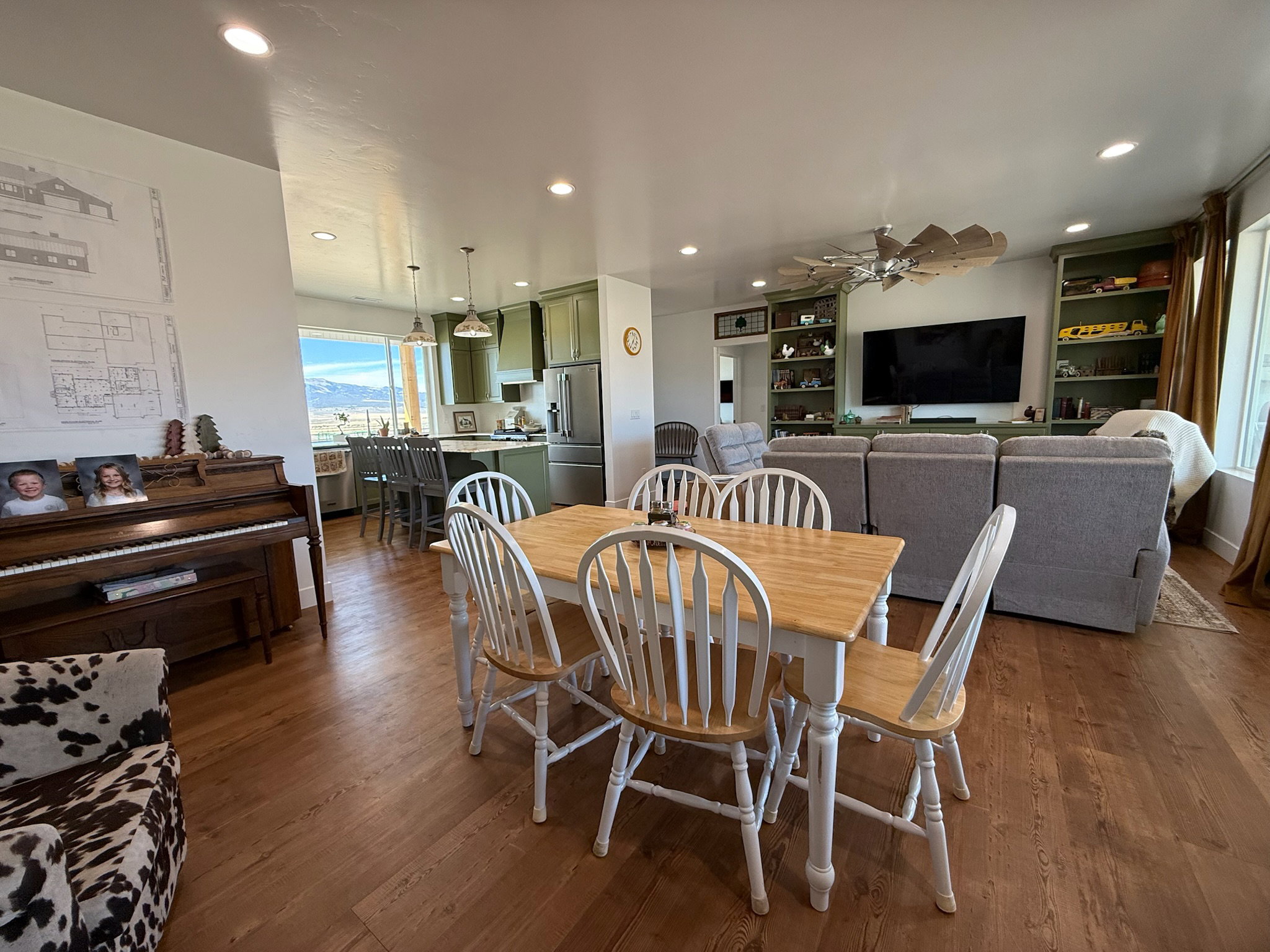 Open-concept living space featuring wood-finish flooring, recessed lighting, and a built-in entertainment center with shelving