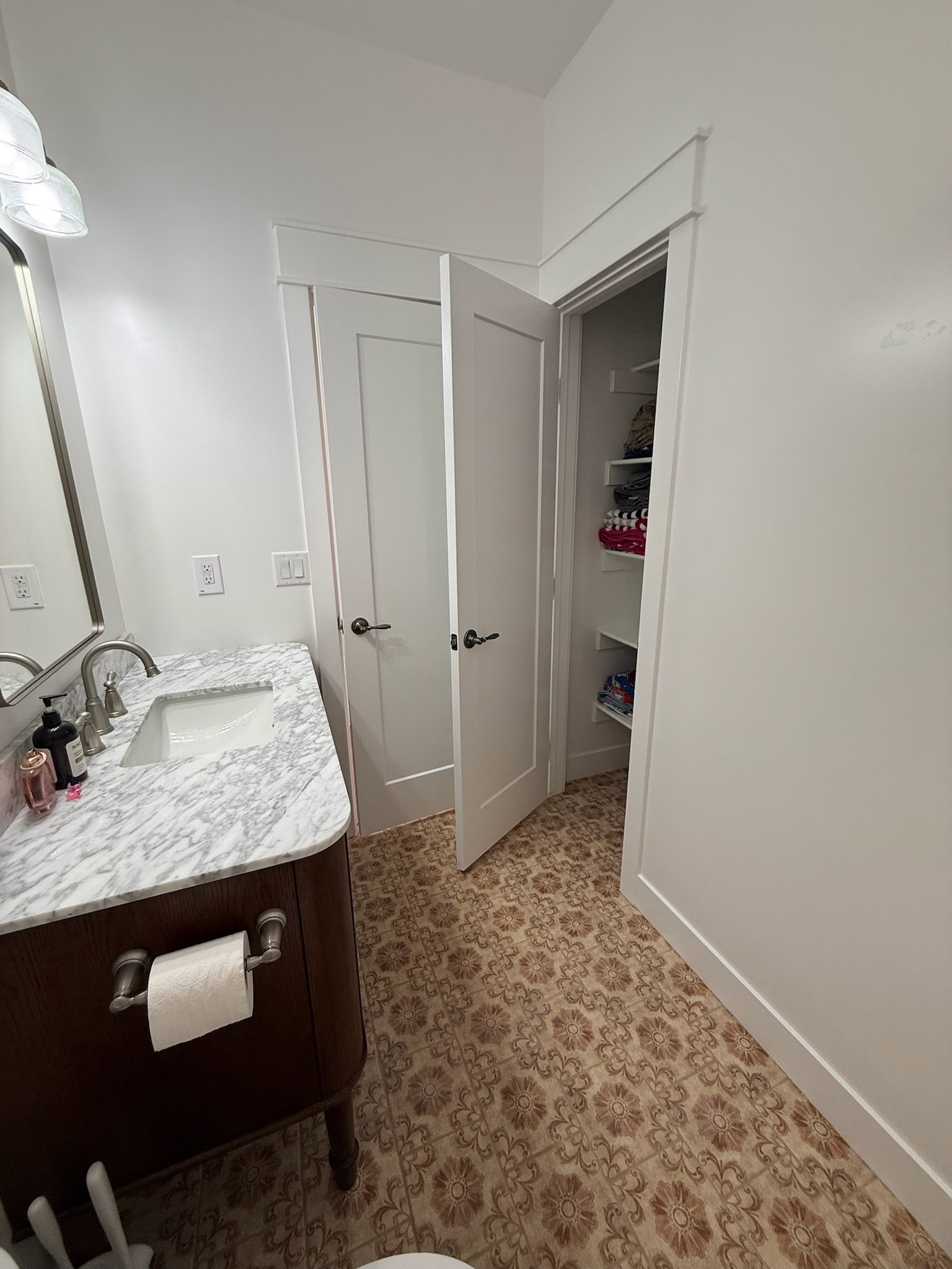 Bathroom featuring a patterned tile floor, a dark wood-finish vanity with a white marble countertop, an undermount sink, and a brushed nickel faucet