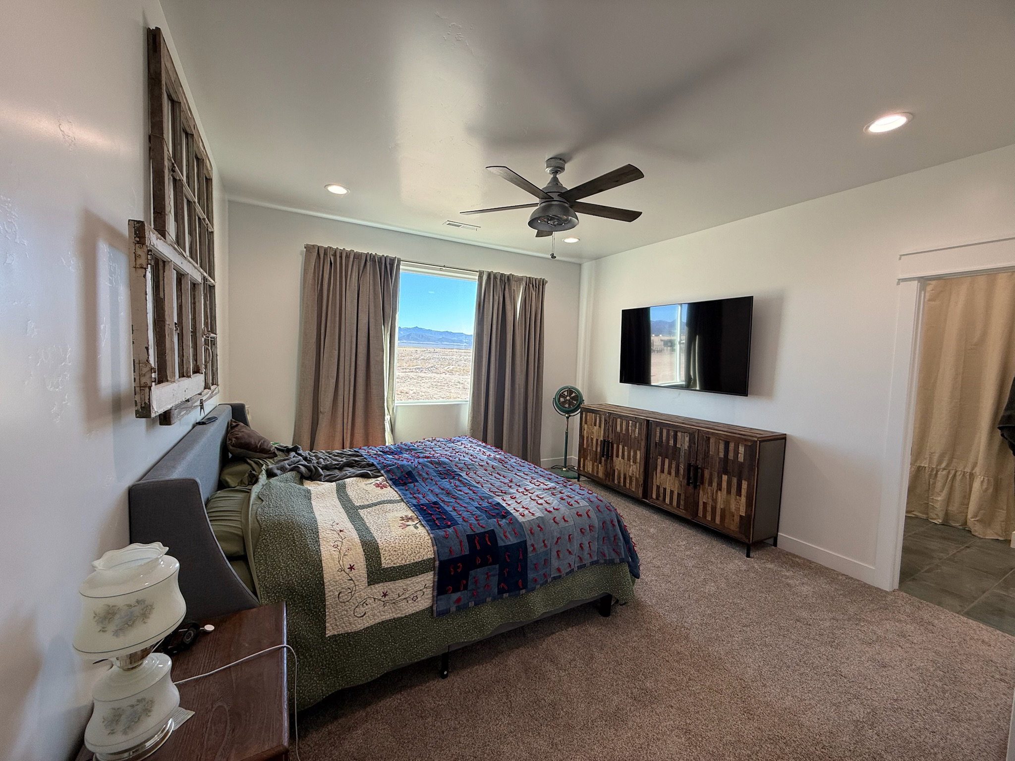 Spacious room featuring a ceiling fan, recessed lighting, and a large window with distant mountain scenery
