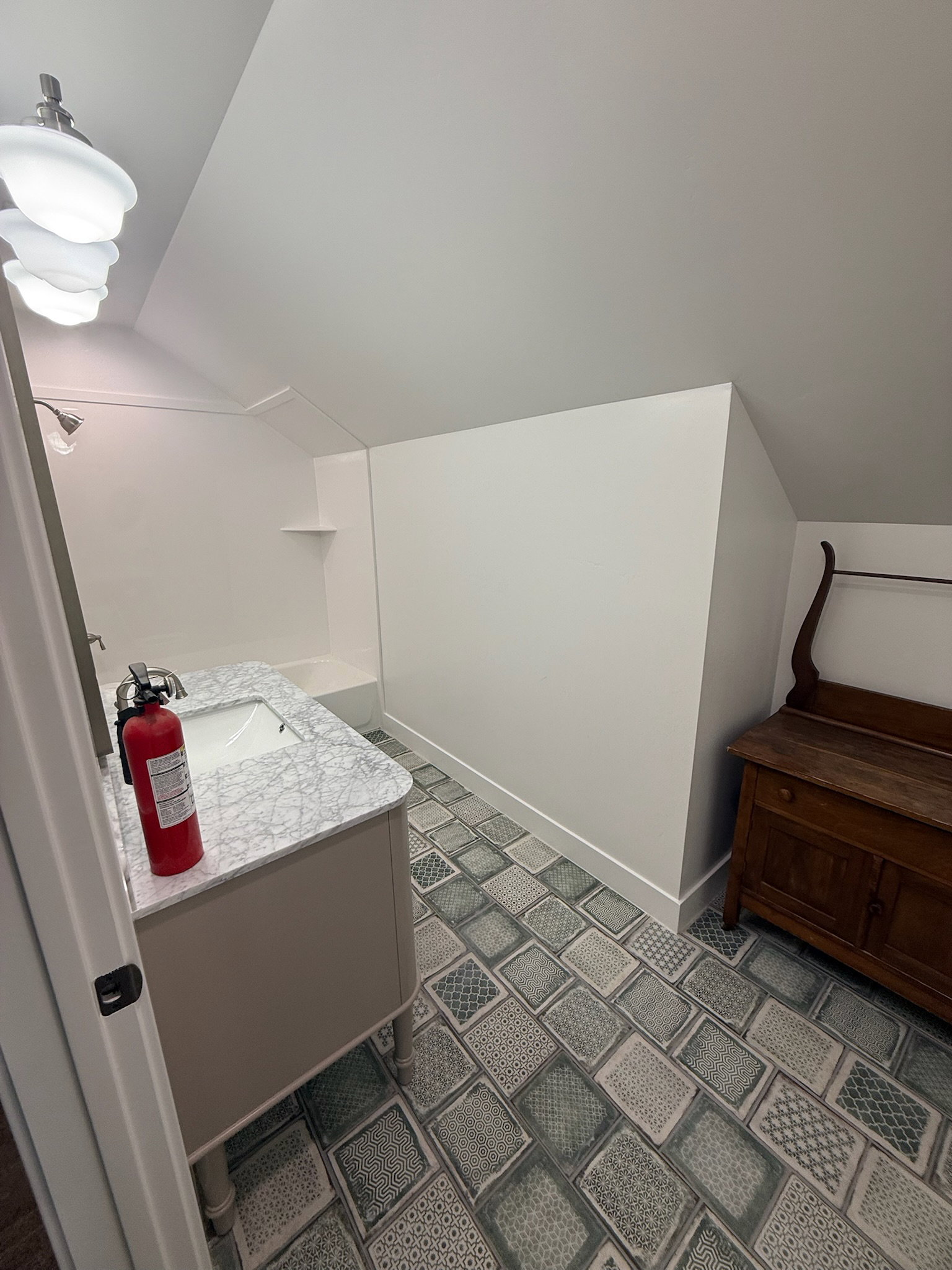 Bathroom featuring a single vanity with stone-finish countertop and undermount sink, patterned floor tile, and a built-in shower/tub combination