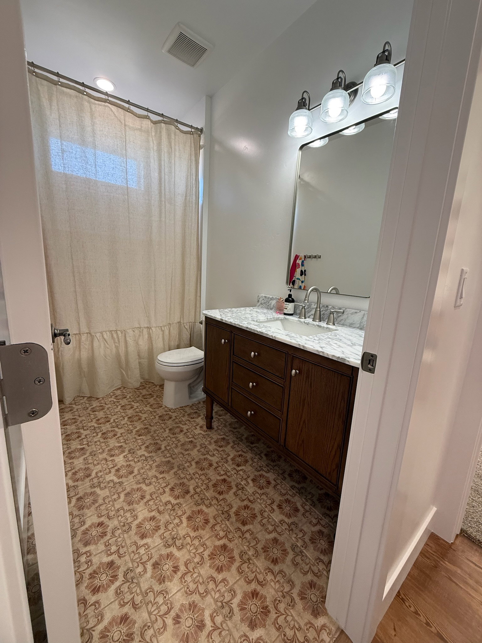 Bathroom featuring a single vanity with a dark wood-finish cabinet, a light-toned countertop, and a rectangular mirror