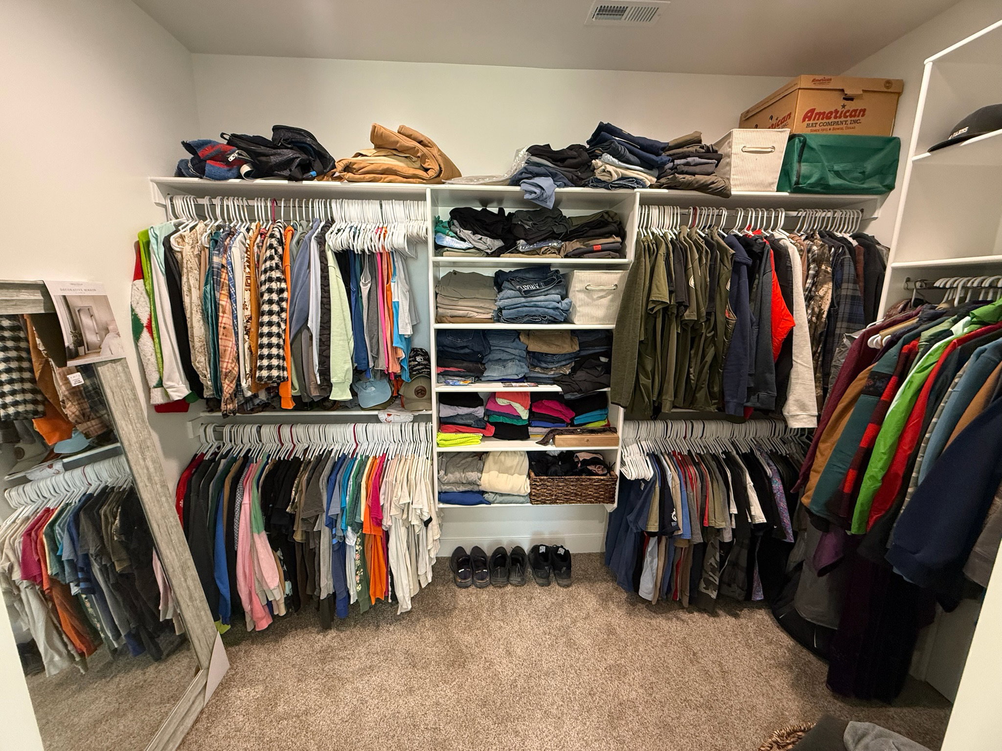Expansive walk-in closet featuring white built-in shelving, multiple hanging rods, and an overhead lighting fixture