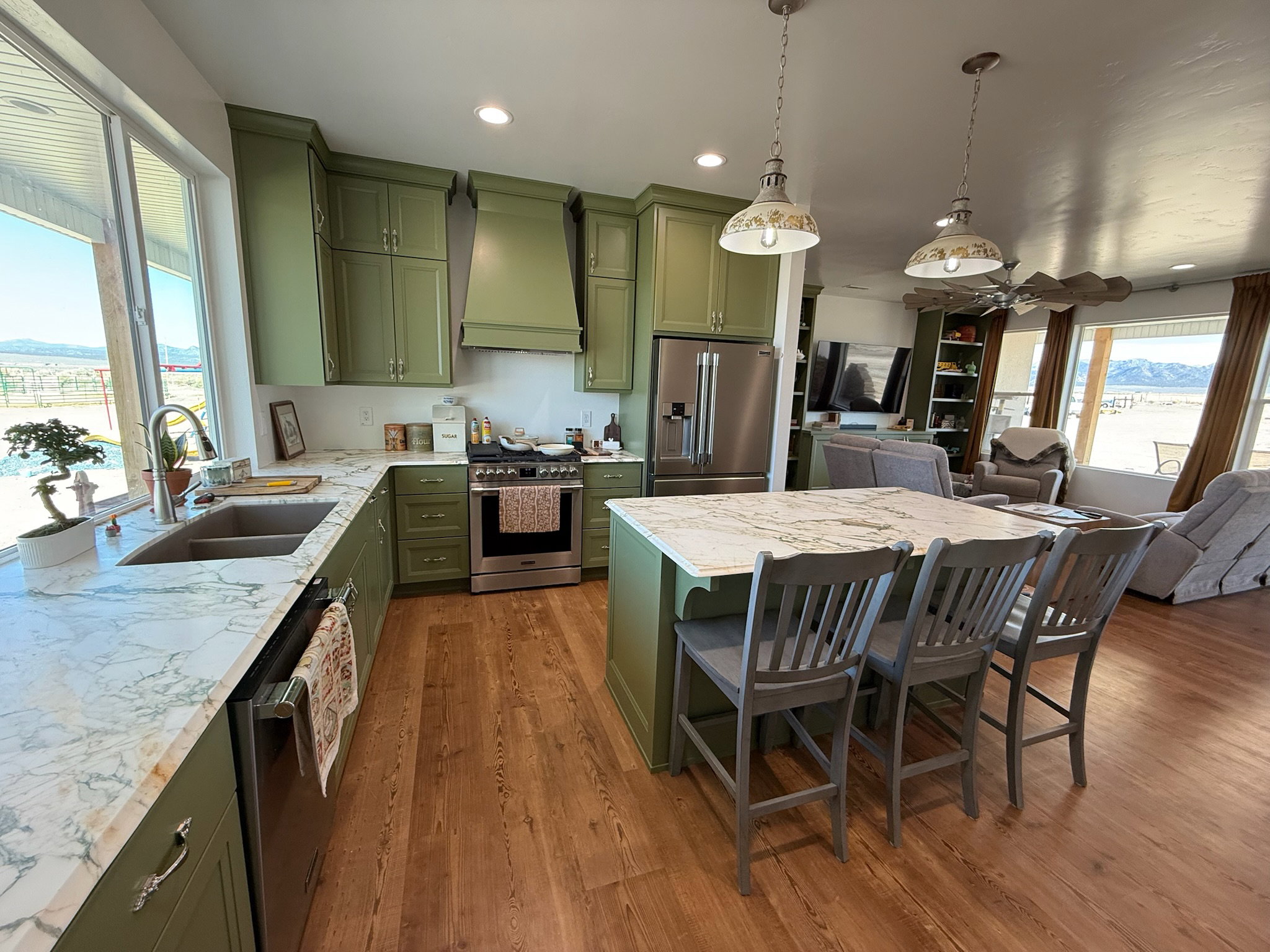 Kitchen featuring green cabinetry, light-toned countertops, stainless steel appliances, and wood-finish flooring