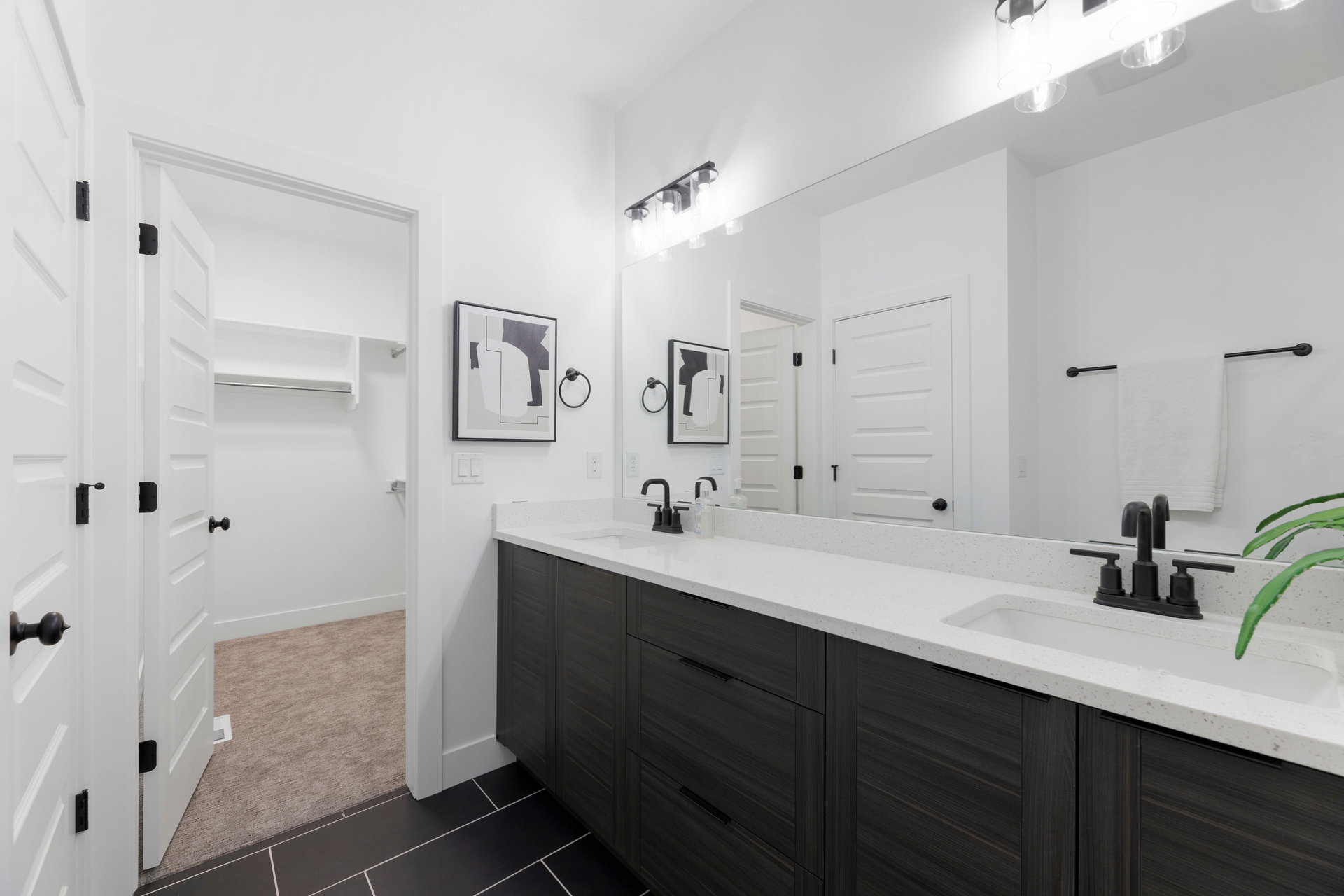 Bathroom featuring double vanity, a spacious closet, dark colored carpet, and dark tile patterned floors