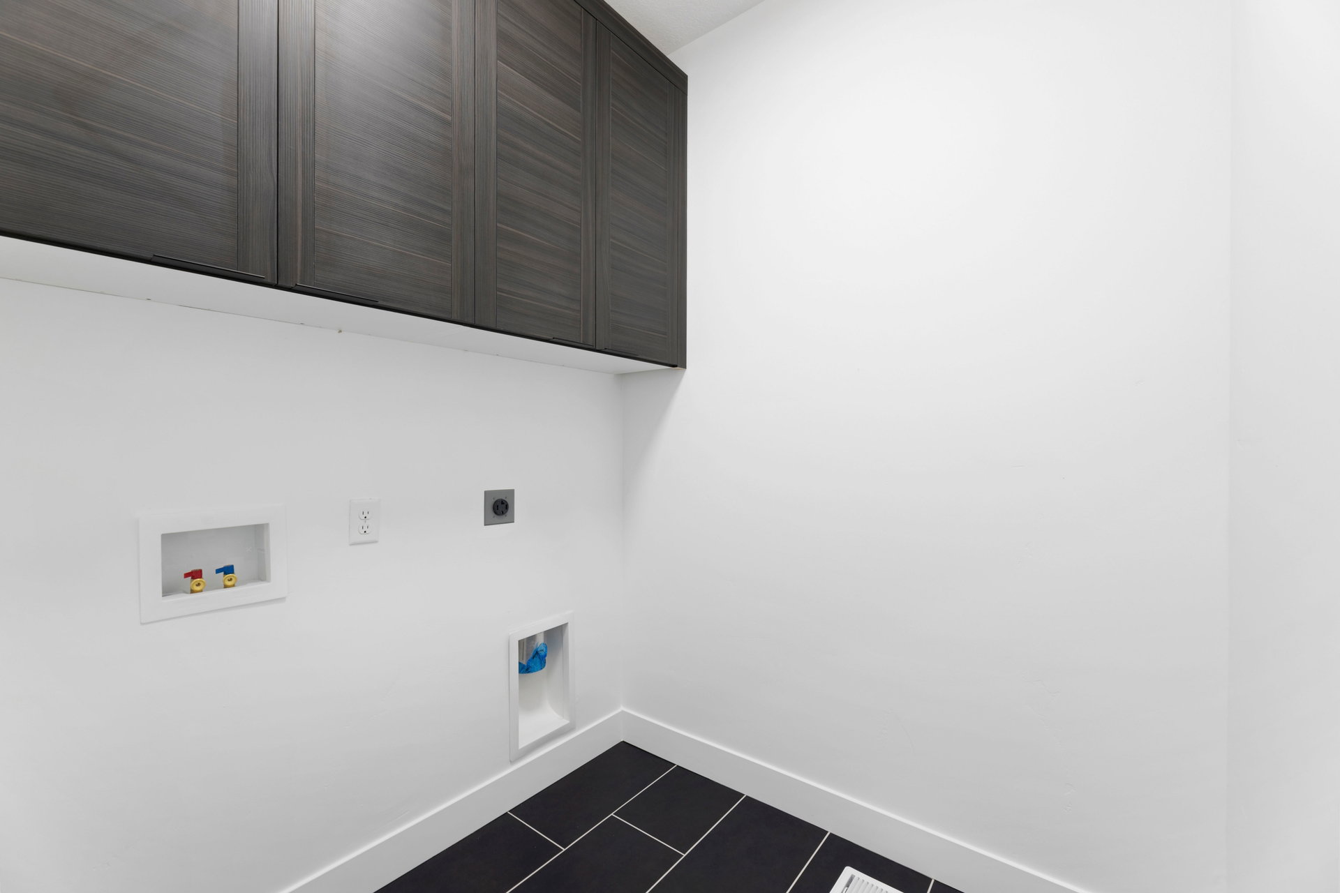 Laundry room with cabinet space, electric dryer hookup, washer hookup, and dark tile patterned flooring